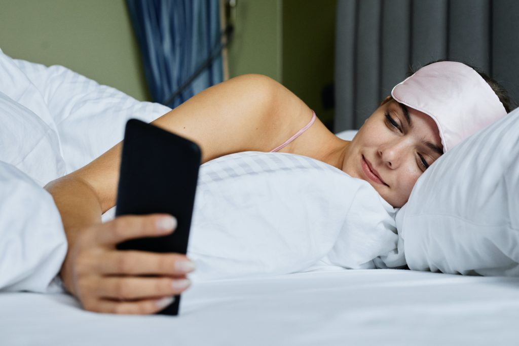 foto ragazza letto cellulare in mano 