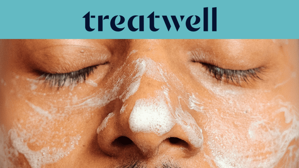 Primo piano del viso di una persona con gli occhi chiusi, coperto da un detergente viso schiumoso bianco. In alto, una fascia azzurra mostra il logo "Treatwell" in blu scuro.