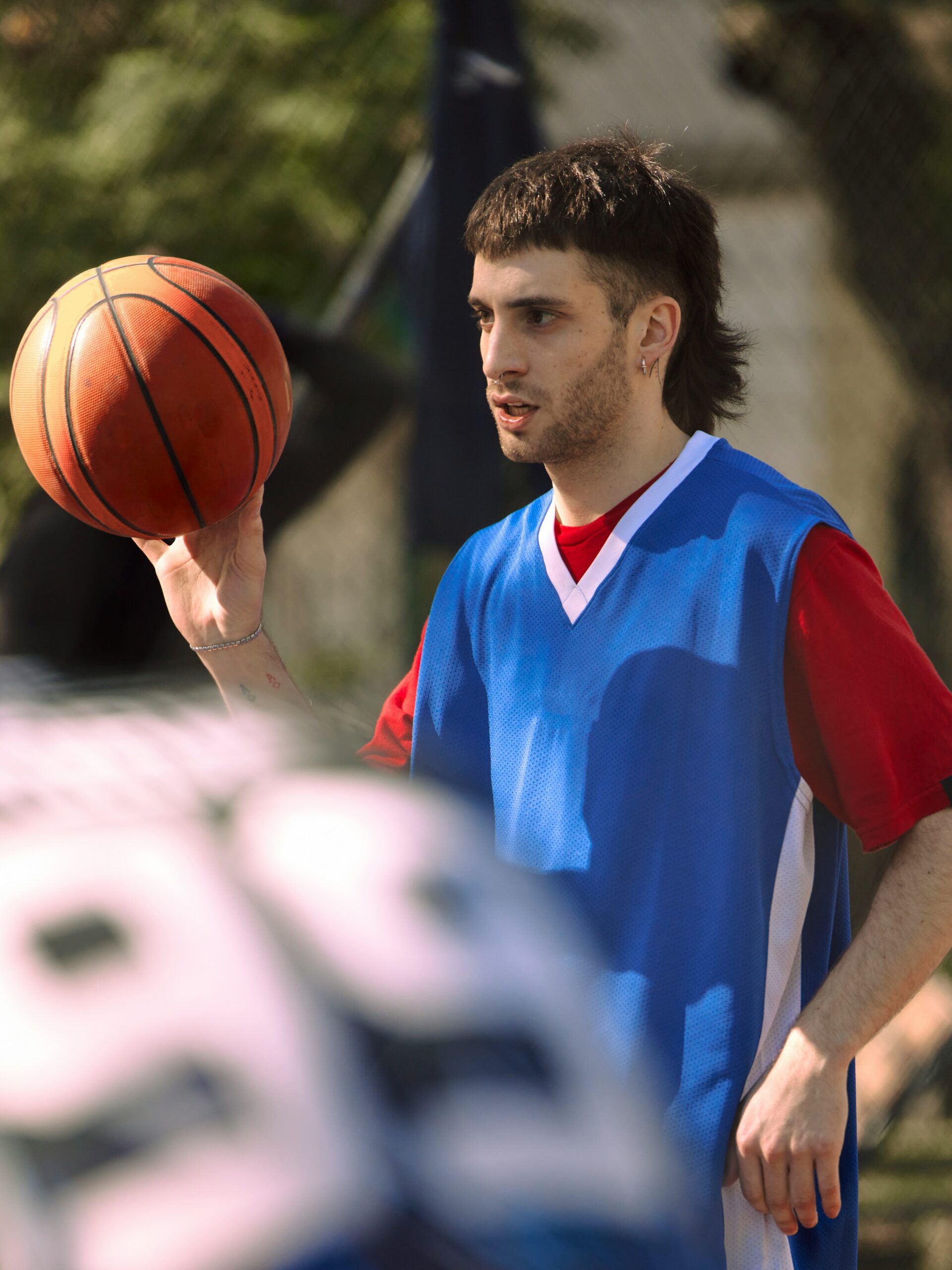 Un giovane uomo con un mullet sfumato che gioca a basket.