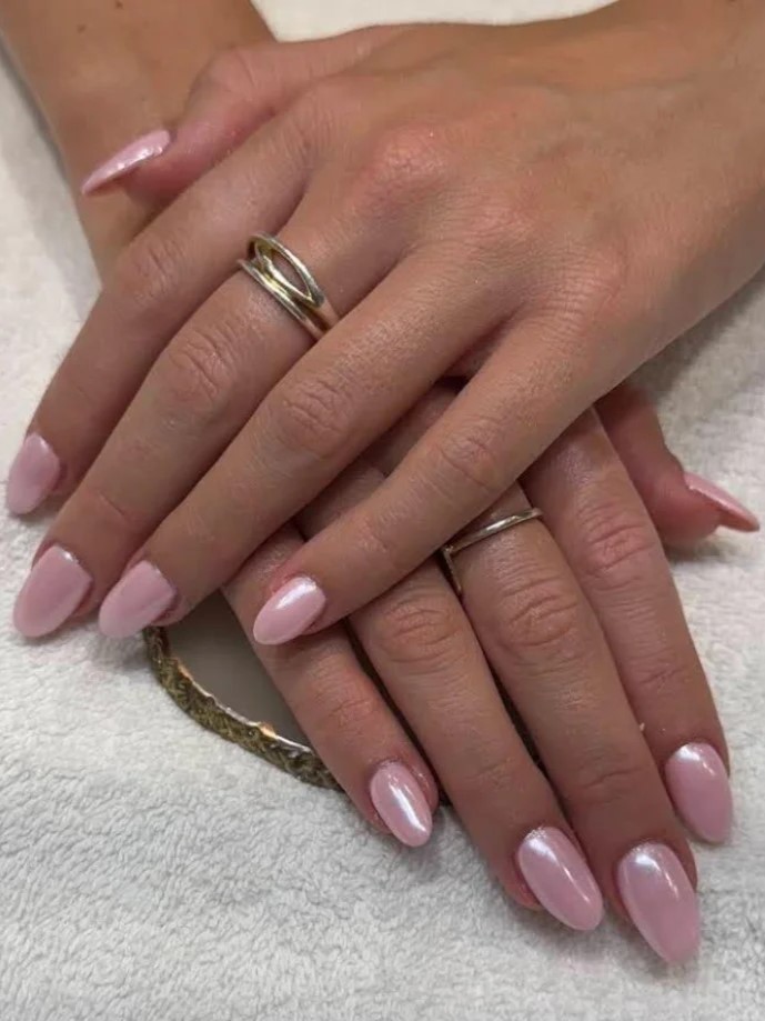 Le mani di una donna intrecciate, con una manicure BIAB rosa acceso e rosso con nail art