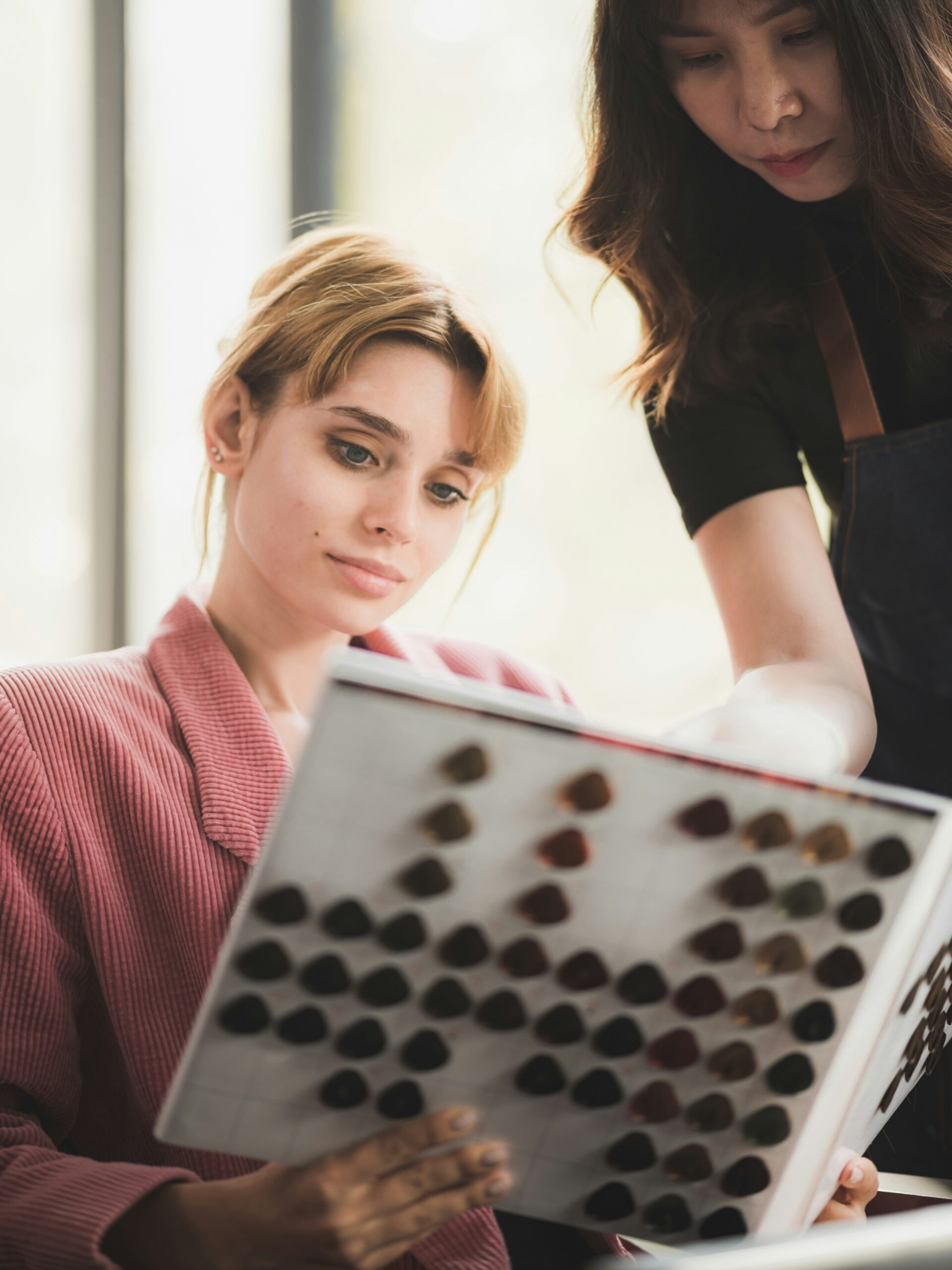 Cliente seduta dal parrucchiere che sfoglia un libro di campioni colore insieme al colorista