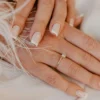 French manicure classica bianca su unghie naturali dalla forma squadrata, su un tessuto bianco