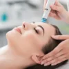 Primo piano di una donna rilassata con gli occhi chiusi durante un trattamento HydraFacial in un salone tranquillo