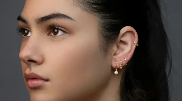 Foto in studio di una donna con un curated ear, con svariati piercing al lobo e un cerchietto all’helix