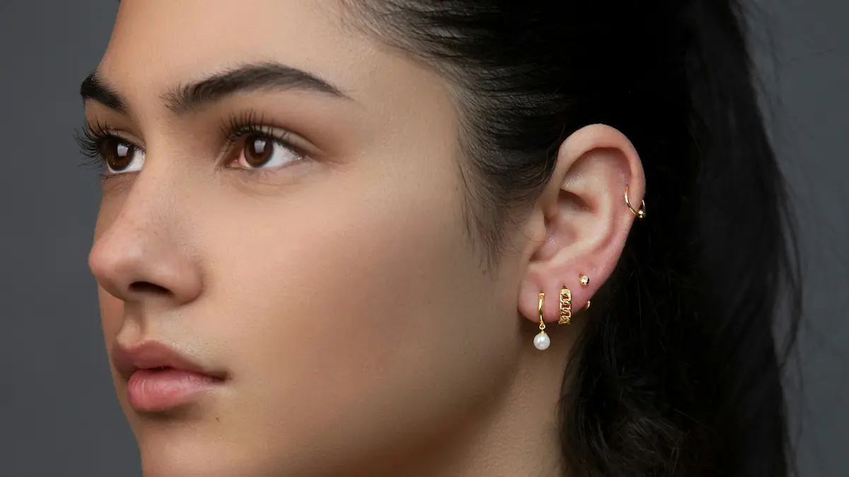 Foto in studio di una donna con un curated ear, con svariati piercing al lobo e un cerchietto all’helix