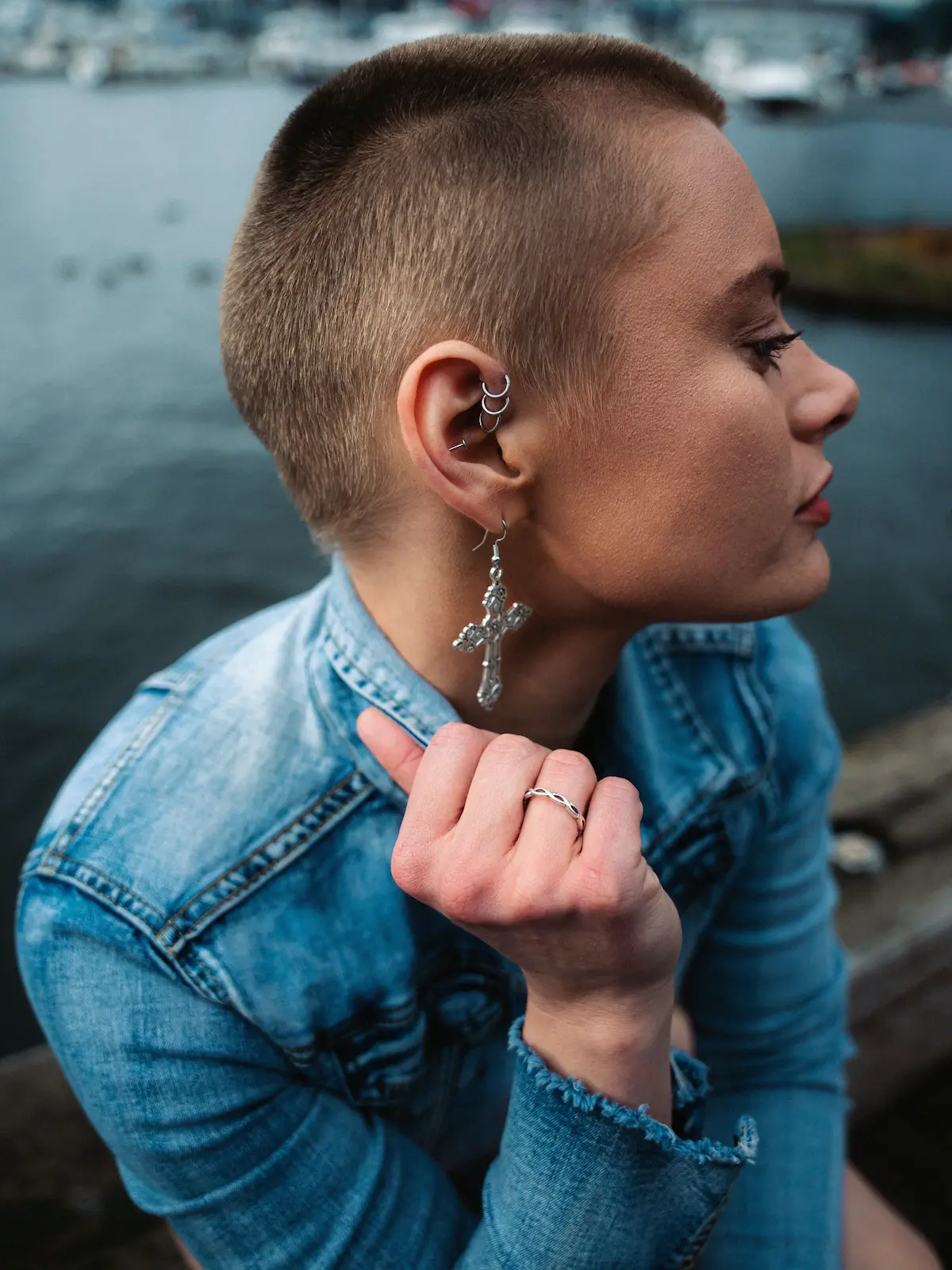 Foto dall’alto di una donna con piercing forward helix, helix e lobo, seduta vicino a un fiume in città