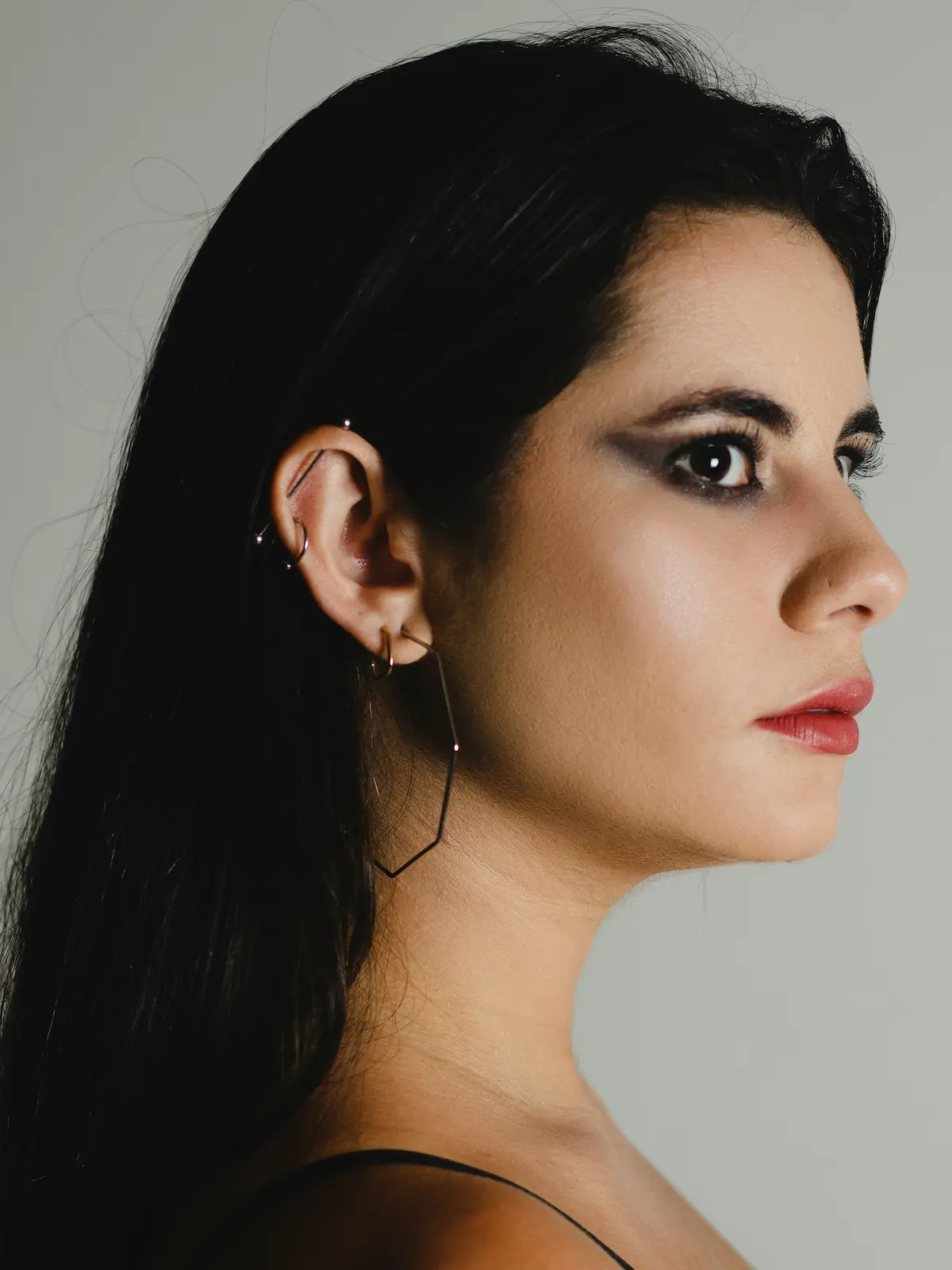 Foto in studio di una donna con un piercing industrial a barbell, piercing al lobo e all’helix