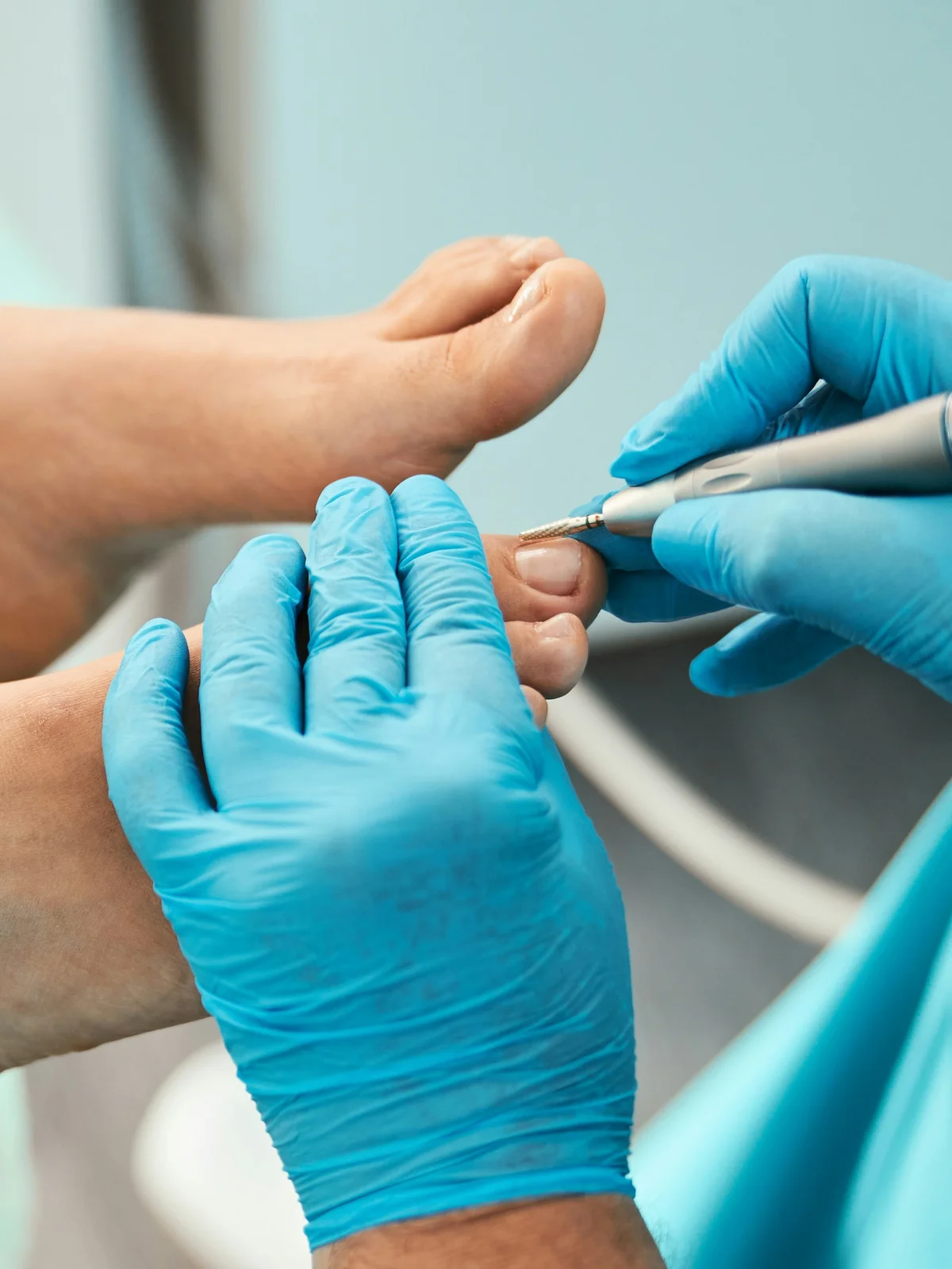 Primo piano di un'estetista con guanto che rifinisce le cuticole delle dita dei piedi di una cliente con un piccolo strumento