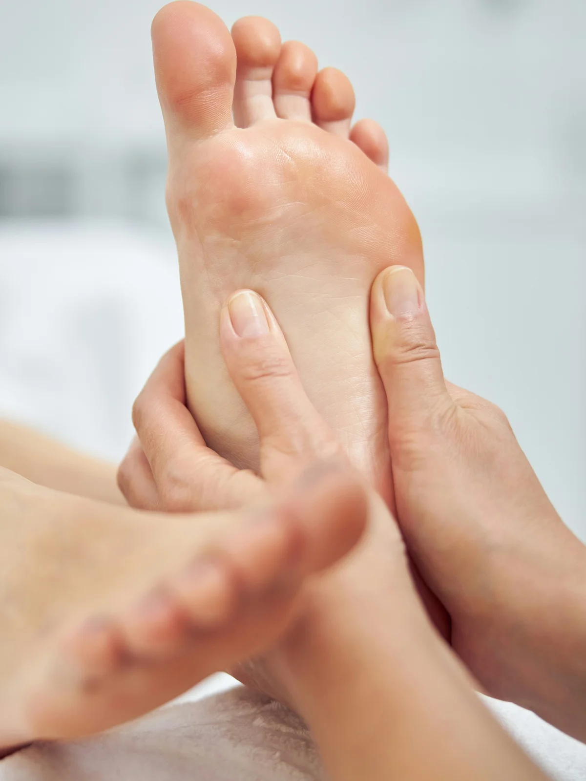 Primo piano di un'estetista che massaggia il piede di una cliente durante una pedicure a secco