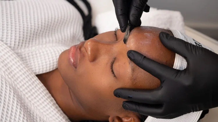 Primo piano di un'estetista che esegue il dermaplaning su una cliente in un centro estetico