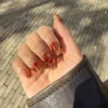 Nail art lava nails con volute ambrate e rosse su base trasparente