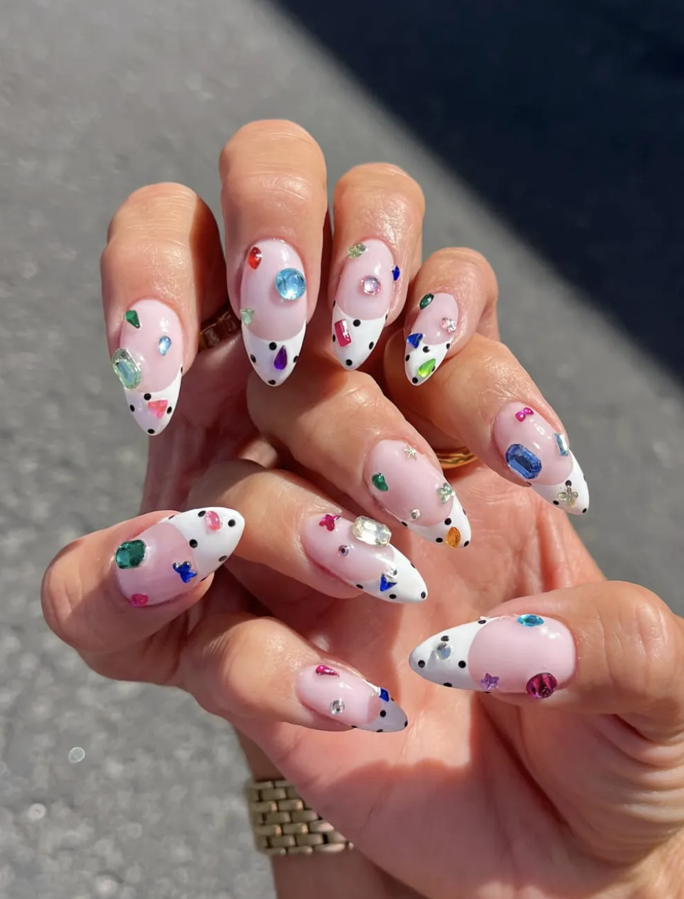 Unghie a mandorla in stile bedazzled con strass colorati e punte bianche a pois